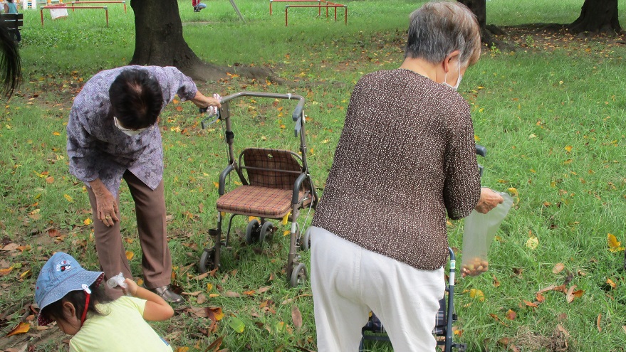 ご利用者さまと子どもたちで公園のどんぐりを拾う様子